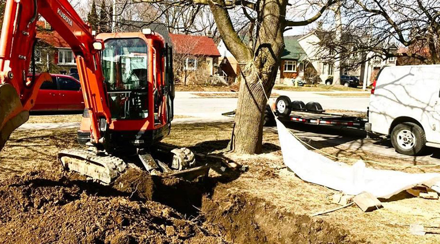 a mechanical digger digging a trench in a garden