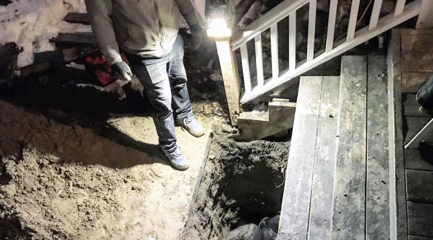 a man standing at a hole at the foot of porch stairs