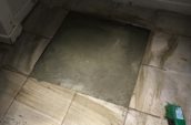 a floor being tiled with an exposed square of cement