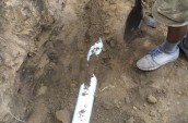 a man standing next to a pipe in the dirt