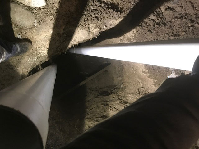 two white pipes emerging from a hole in the ground
