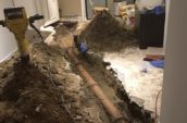 a trench in a room revealing a water pipe