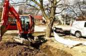 a mechanical digger digging a trench in a garden