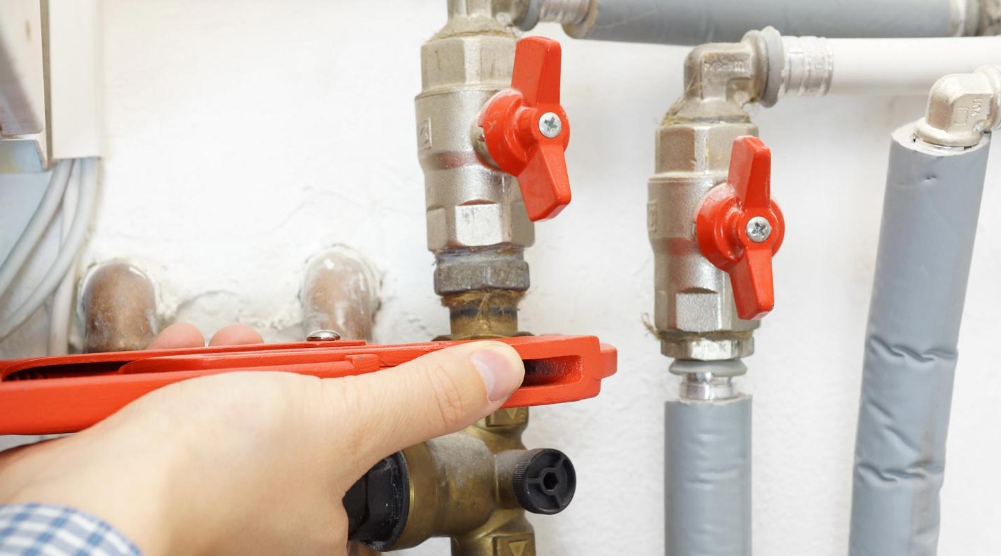 a person is fixing a water heater with a wrench