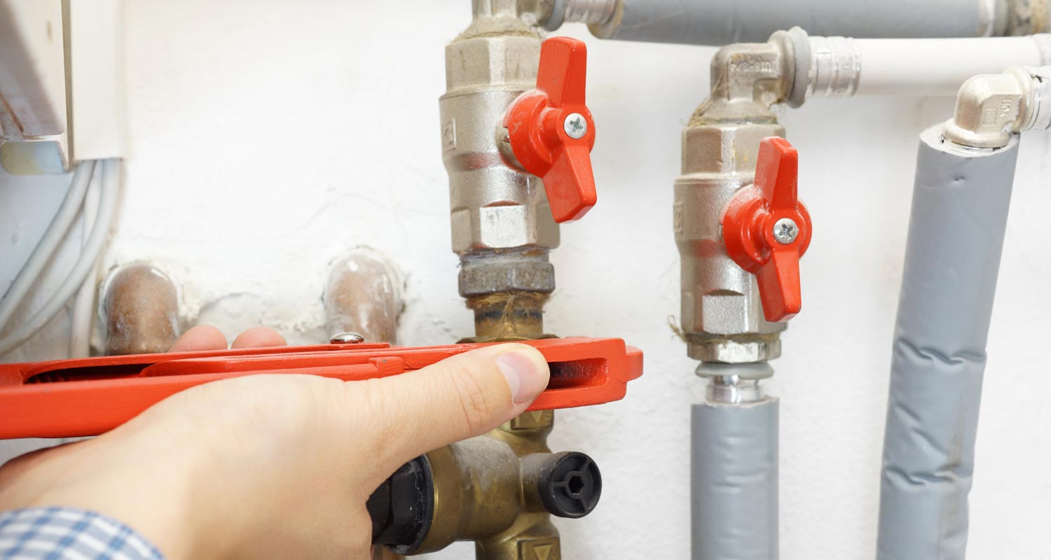 a person is fixing a water heater with a wrench